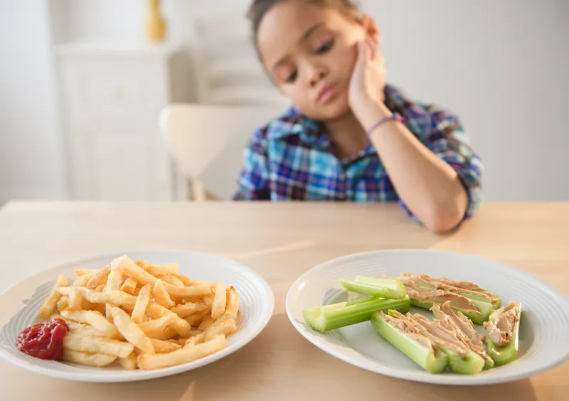 African American girl looking at healthy and unhealthy food