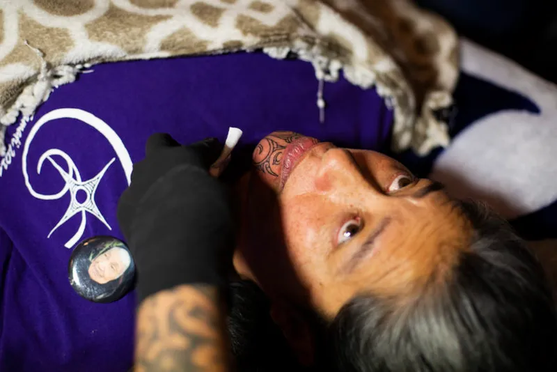 As the finishing touches are added to the Moko kauae (Maori chin tattoo for women), Maxine Te Rongomau looks up at ta...
