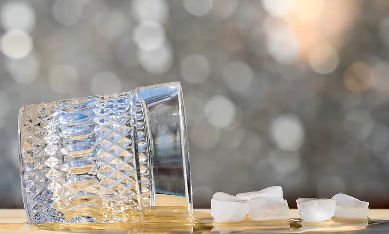 Glass of wisky with fallen ice on a table
