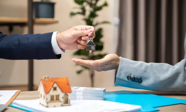 Estate agent giving house keys to client after signing agreement contract real estate with approved mortgage application form, concerning mortgage loan offer for and house insurance