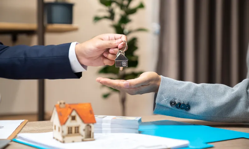 Estate agent giving house keys to client after signing agreement contract real estate with approved mortgage application form, concerning mortgage loan offer for and house insurance