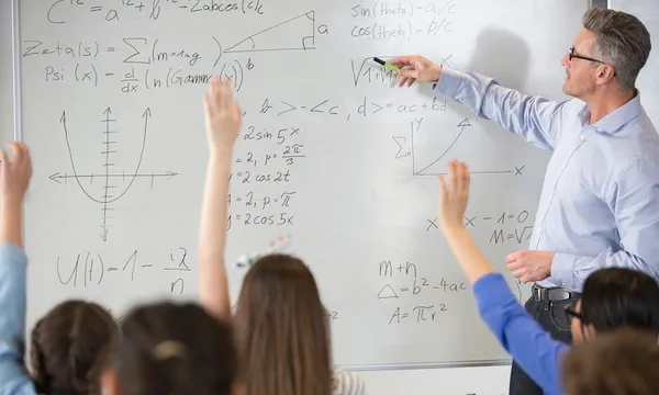 Male teacher leading physics lesson at whiteboard in classroom