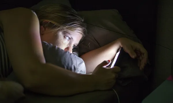 Caucasian woman using cell phone in bed