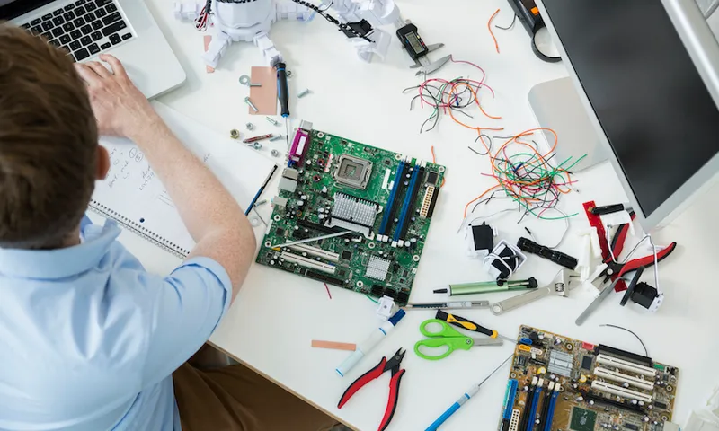Engineer assembling circuit boards and working at laptop. SAIT Aldred Centre, 1301, 16 Ave NW, Calgary, AB, Canada.