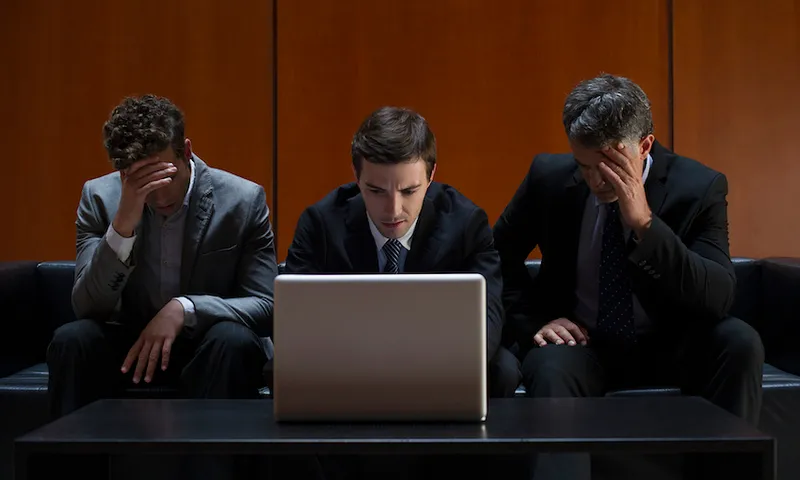 Business confidence financial crisis Disappointed business associates sitting side by side on sofa looking at laptop computer