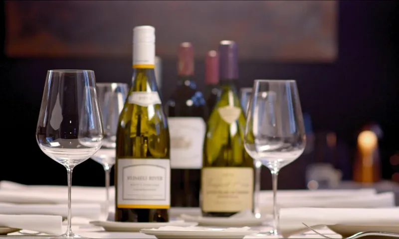 two bottles of wine next to a wine glasses indoors at night