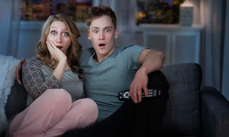 Young couple watching TV at night