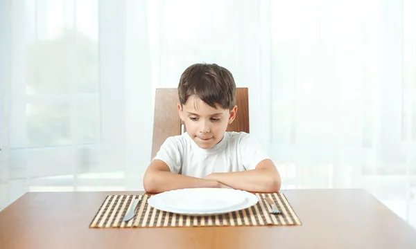 Boy sitting at dinner table waiting for food