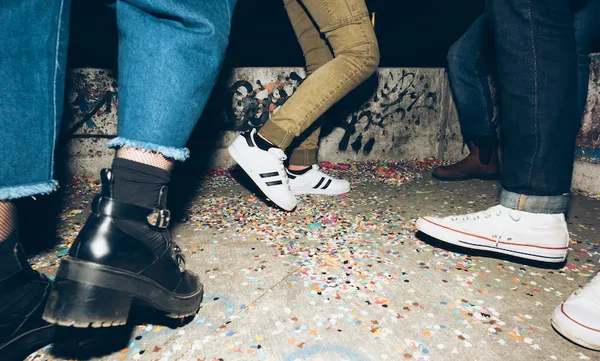 Group of friends, standing outdoors, confetti on floor, low section