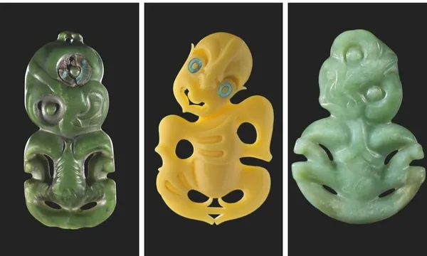 Three traditional Māori hei-tiki pendants are displayed vertically. The pendants are carved from greenstone and yellow stone, each featuring a stylized humanoid form with large eyes and intricate detailing. Black background.