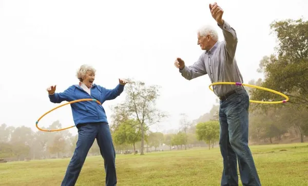 Husband and wife playing hula hoop in the park