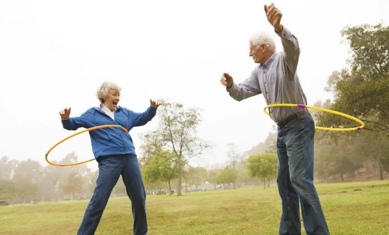 Husband and wife playing hula hoop in the park