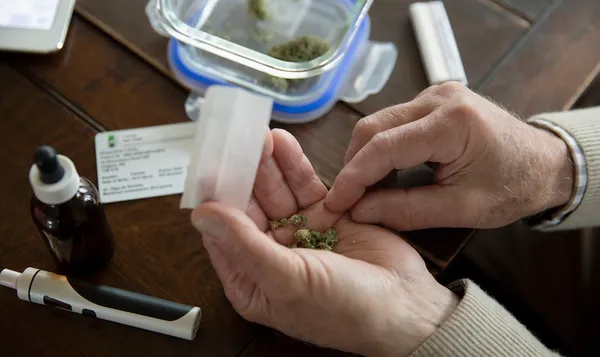Close up senior man rolling medicinal marijuana joint