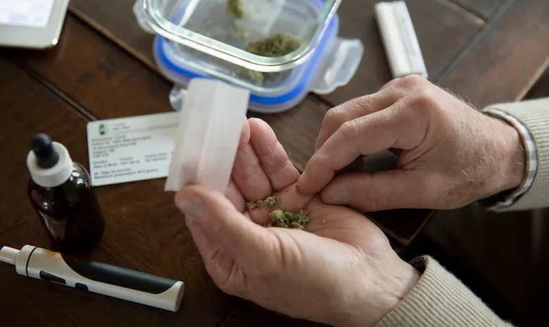 Close up senior man rolling medicinal marijuana joint