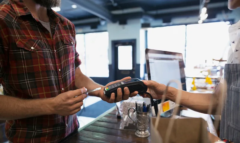 Man paying with credit card reader in shop