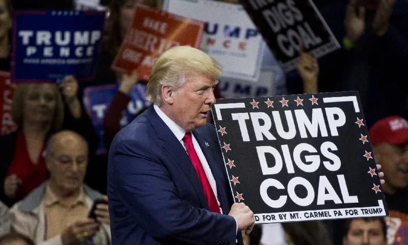 trump holding a “trump digs coal” sign