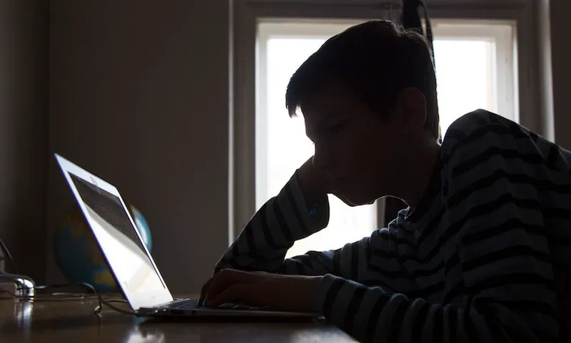 A Boy Sitting At A Laptop