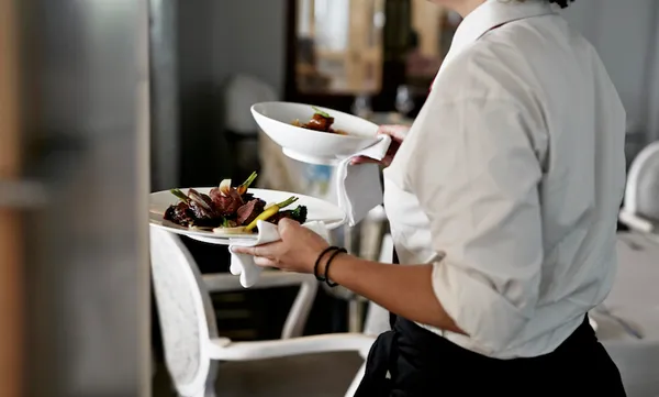 Waiter walking with dishes inside restaurant