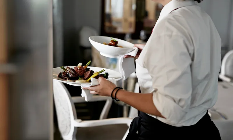 Waiter walking with dishes inside restaurant