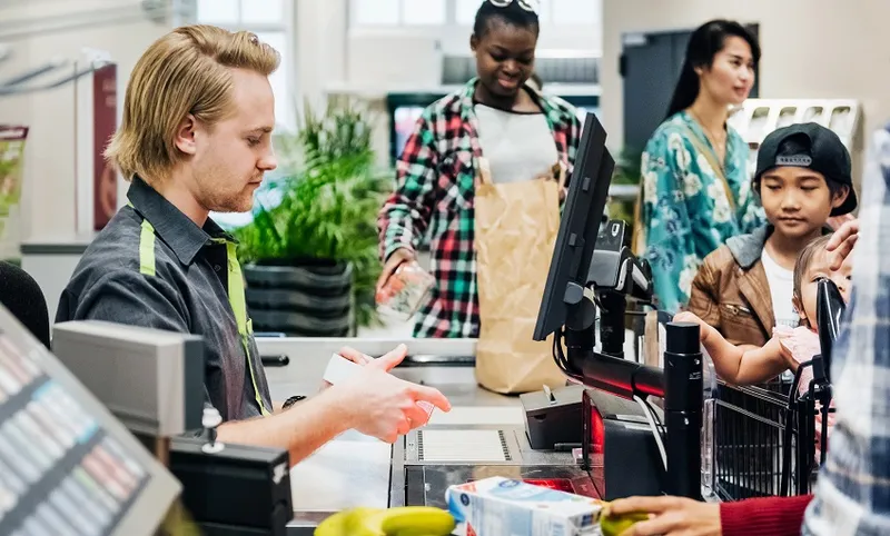 Cashier Working At Busy Checkout
