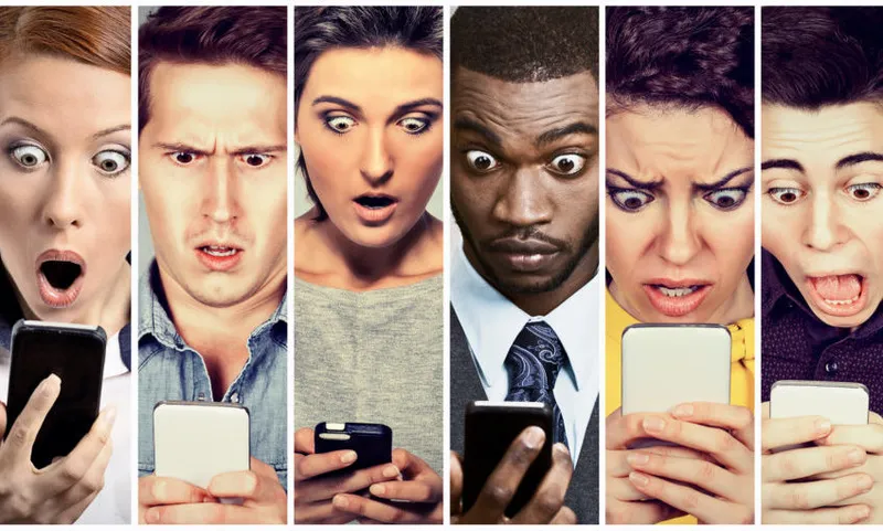 Multicultural group of young people men and women looking shocked at mobile phone