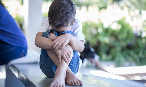 Boy sitting on floor hiding his face