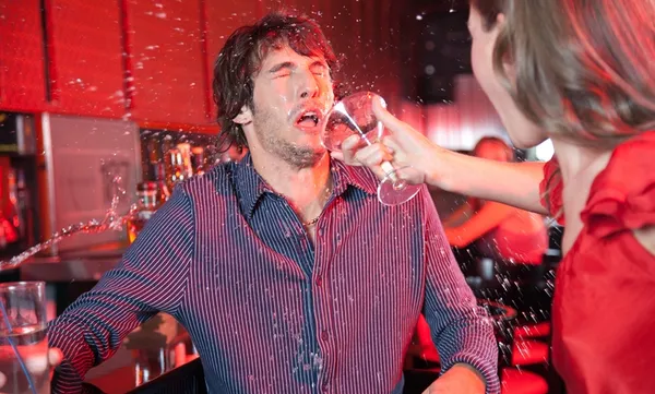 Woman in nightclub throwing beverage in man’s face