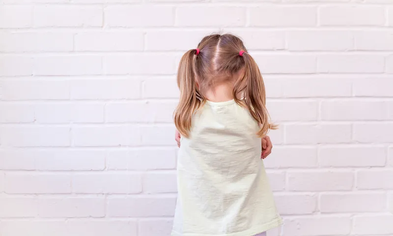 Girl Standing Against White Wall