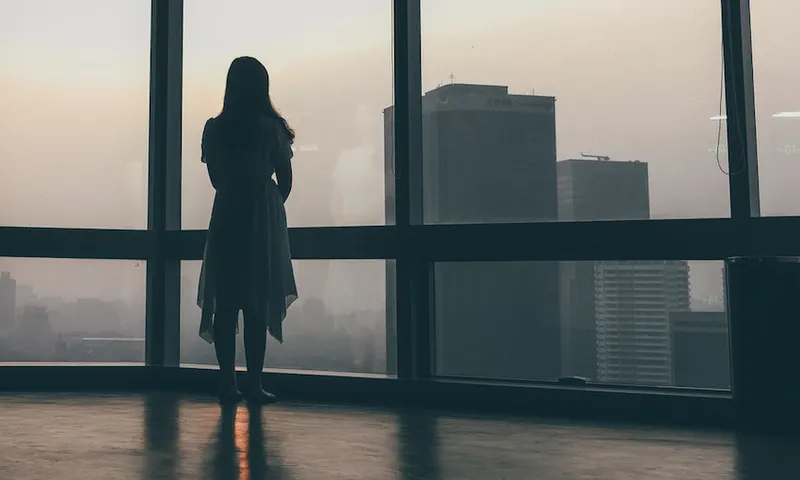 Woman looking out of window of office