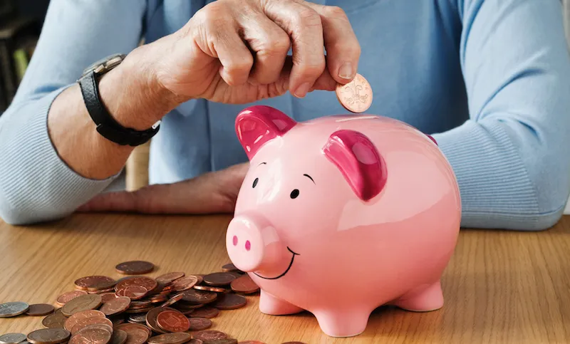 Senior woman inserting coins into piggybank