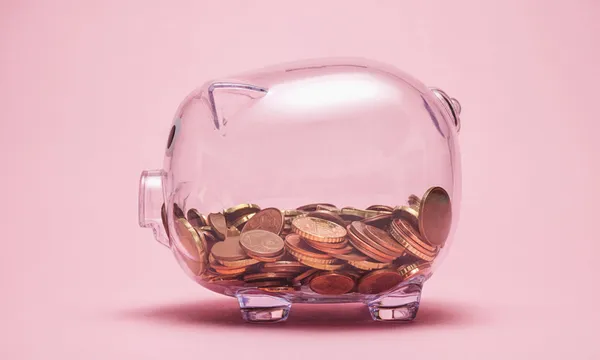 Close-Up Of Coin In Piggy Bank Against Pink Background