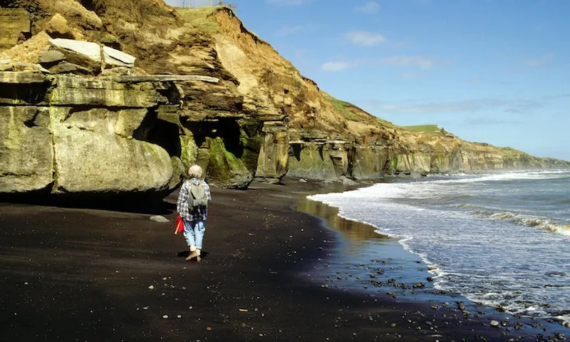 Black iron sands, Geologist at base of muddy sand siltstones, South Taranaki coast, New Zealand