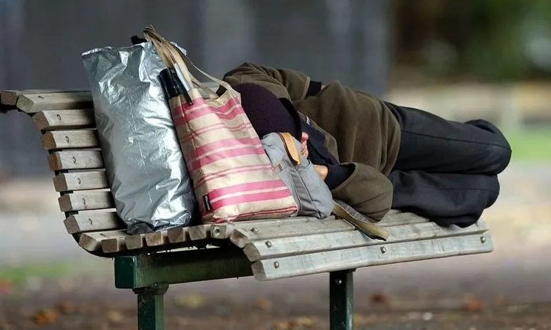 Homeless person sleeping on a park bench at Victor