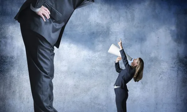 Businesswoman Shouts Through Megaphone Towards Much Larger Businessman