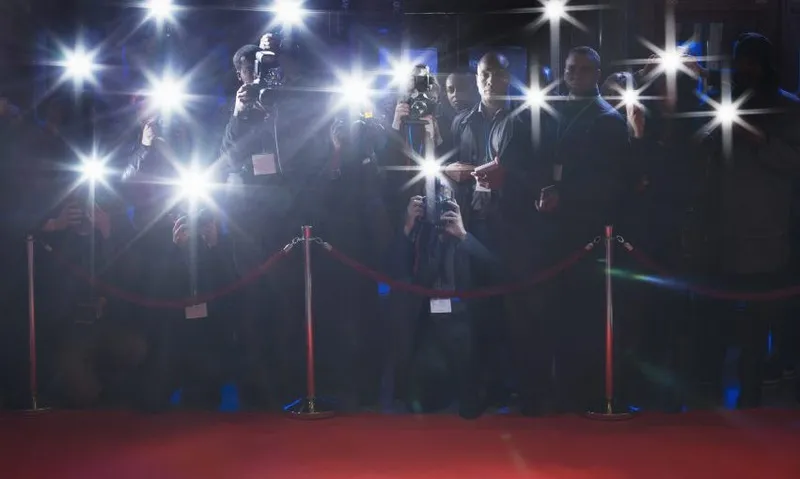 Paparazzi using flash photography behind rope on red carpet