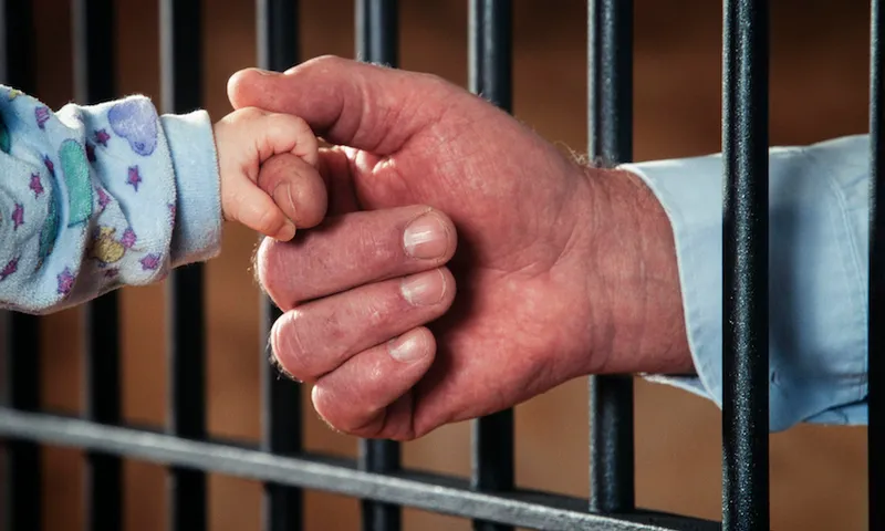 Hand of a prisoner holding a baby's hand