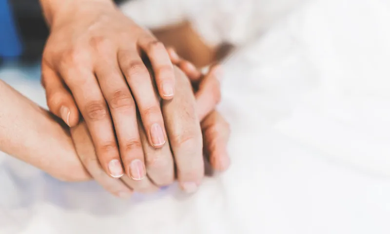 Cropped image of nurse holding man’s hand