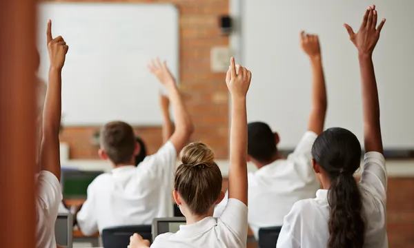 School students with raised hands, back view