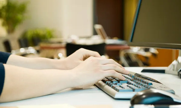 Person typing on computer keyboard, cropped
