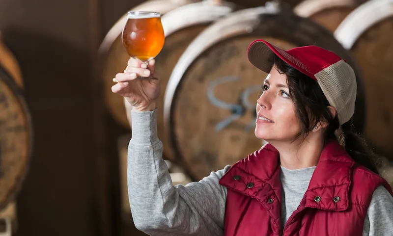 Worker in a microbrewery inspecting glass of beer
