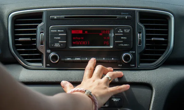 Cropped Hand Of Woman Operating Radio In Car
