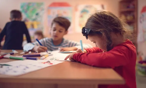 Small girl drawing on a class in a preschool.