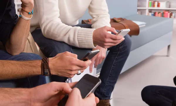 Young students texting on cell phones, close up