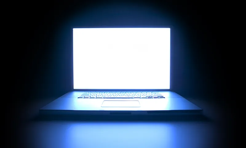 shot of a laptop computer as the screen glows in the darkness