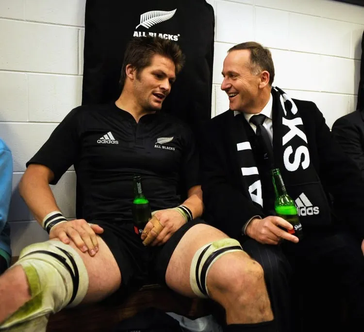 WELLINGTON, NEW ZEALAND - SEPTEMBER 19:  All Black captain Richie McCaw (L) enjoys a beer with New Zealand Prime Minister John Key in the dressing shed following the 2009 Tri Nations series Bledisloe Cup match between the New Zealand All Blacks and the Australian Wallabies at Westpac Stadium on September 19, 2009 in Wellington, New Zealand.  (Photo by Ross Land/Getty Images)