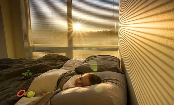 Baby Boy Sleeping On Bed At Home During Sunrise