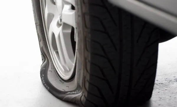 A flat tire is the focus isolated on white