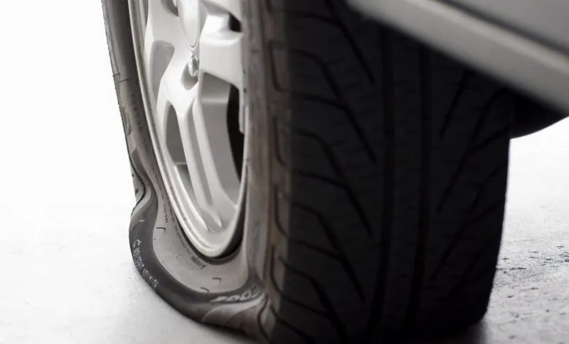A flat tire is the focus isolated on white