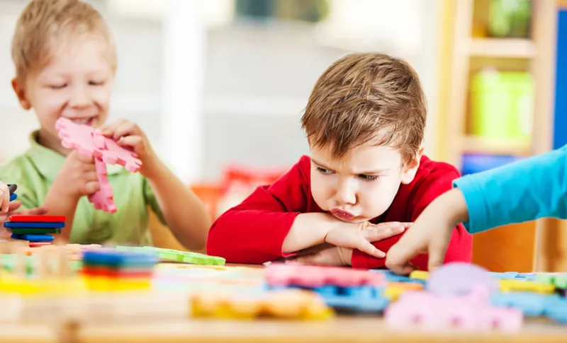 Angry little boy looking at puzzles.