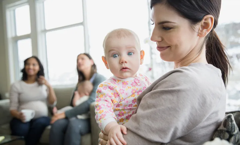 Mother holding curious baby in living room